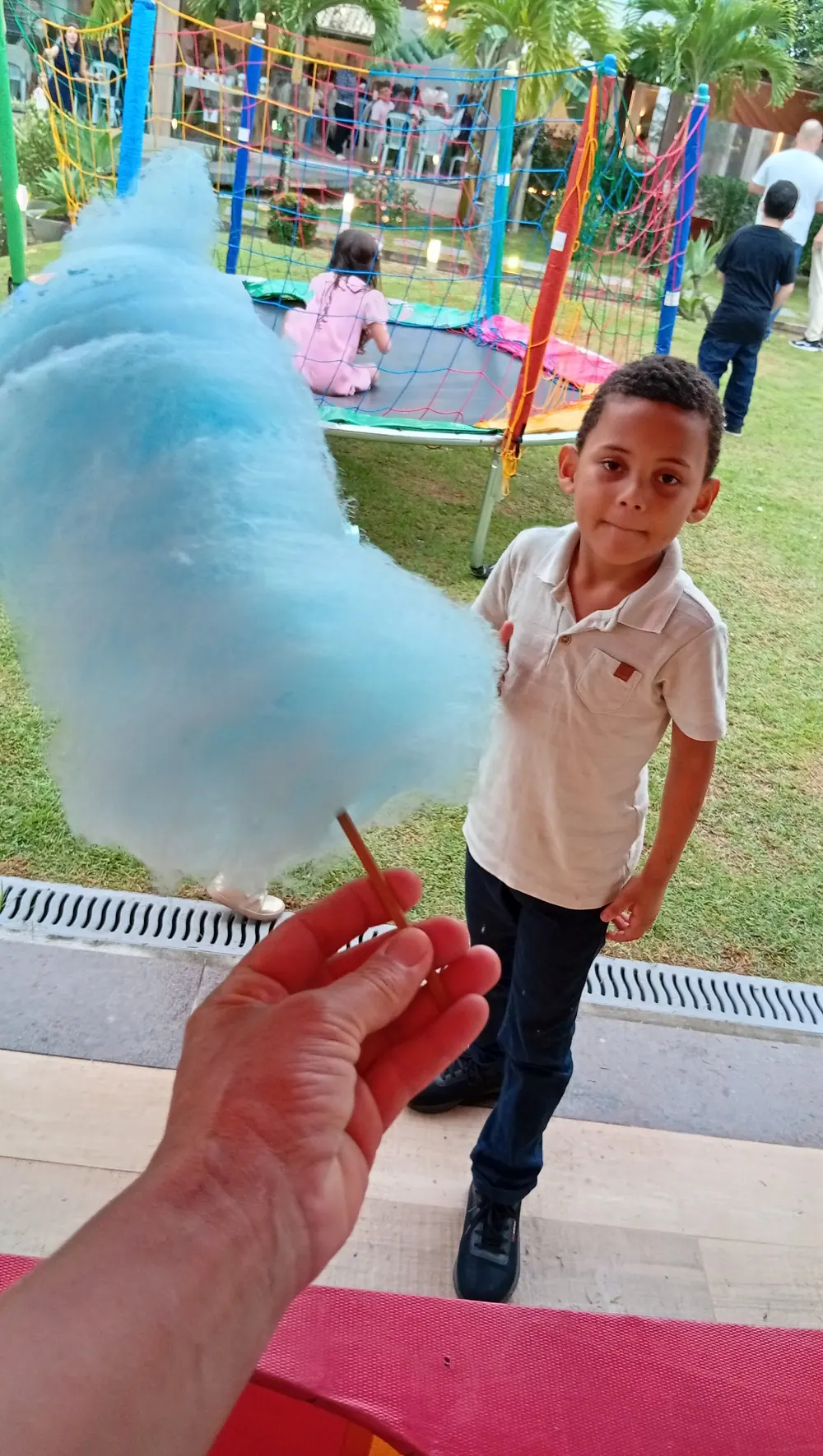 Menino recebendo um algodão doce azul na festa
