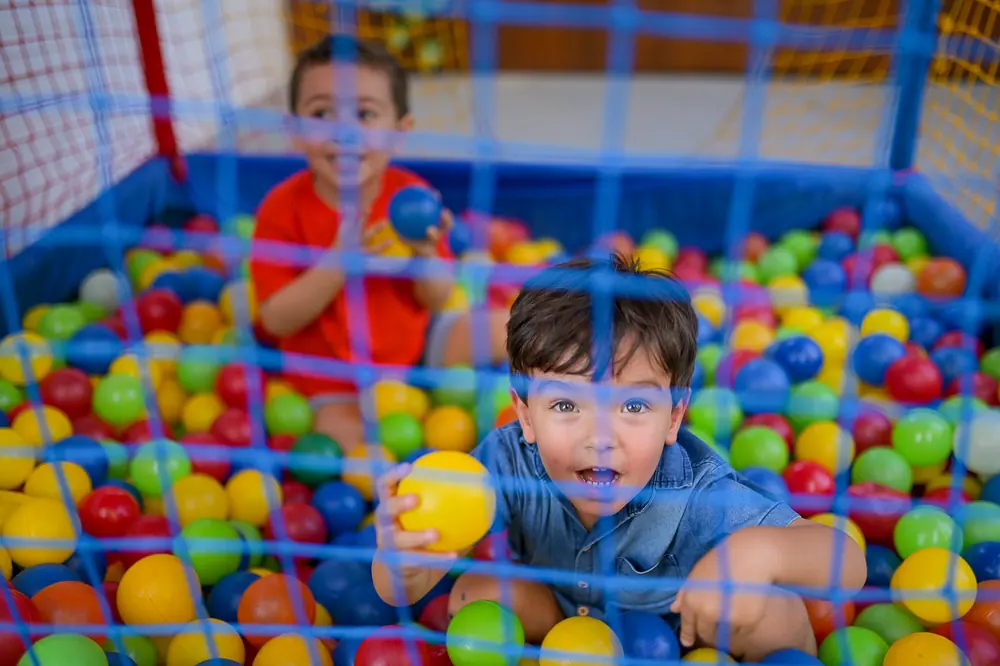 Dois meninos brincando dentro da piscina de bolinhas