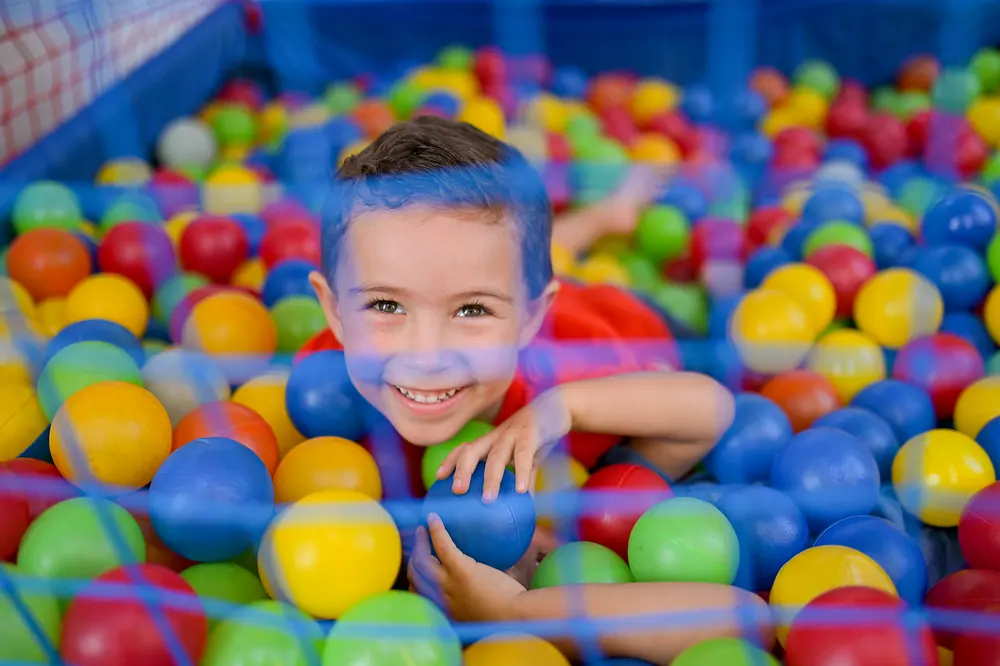 Menino sorrindo no meio das bolinhas coloridas