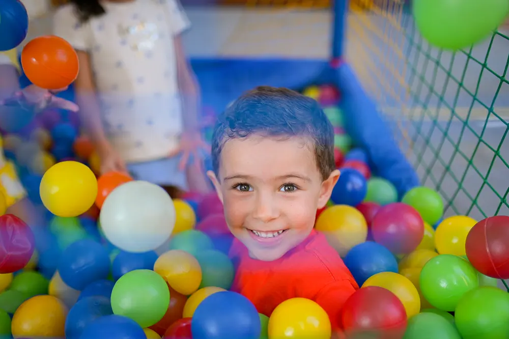 Criança brincando com as bolinhas coloridas na piscina