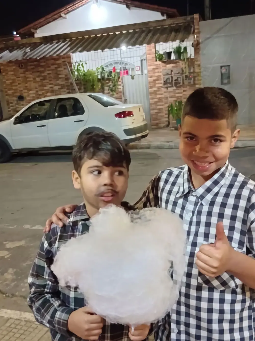Dois meninos posando com um algodão doce grande